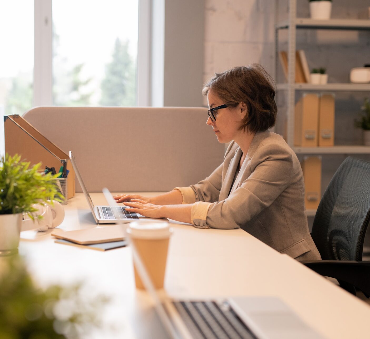 Serious concentrated office lady in glasses sitting at table